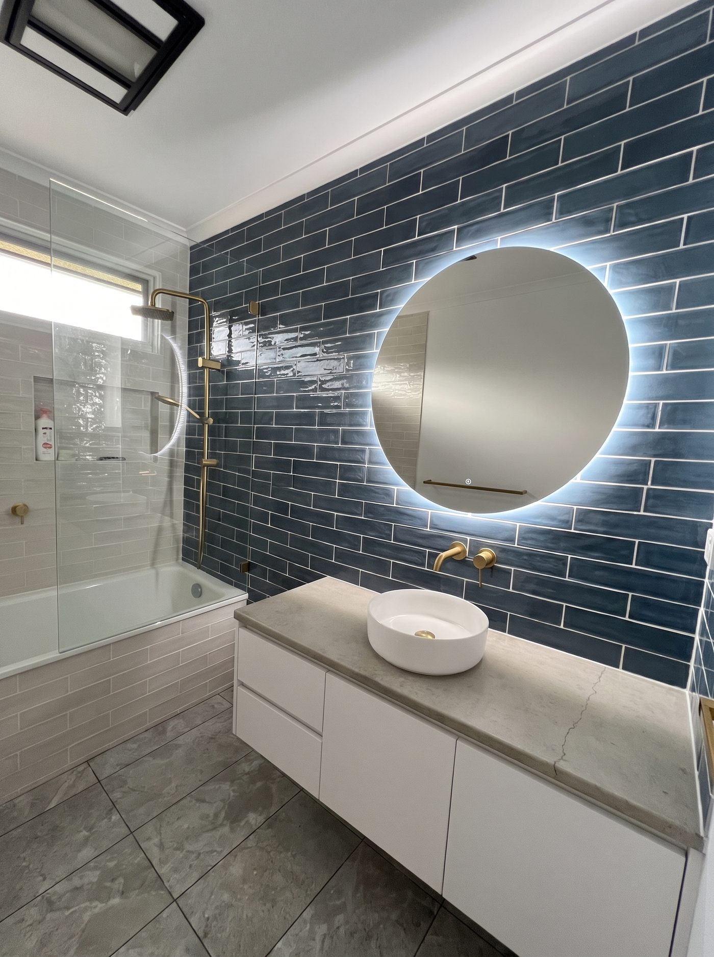 Bathroom with blue subway tile feature wall, freestanding bath and gold tapware